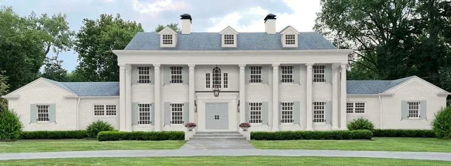 A large white house with a blue roof is surrounded by trees