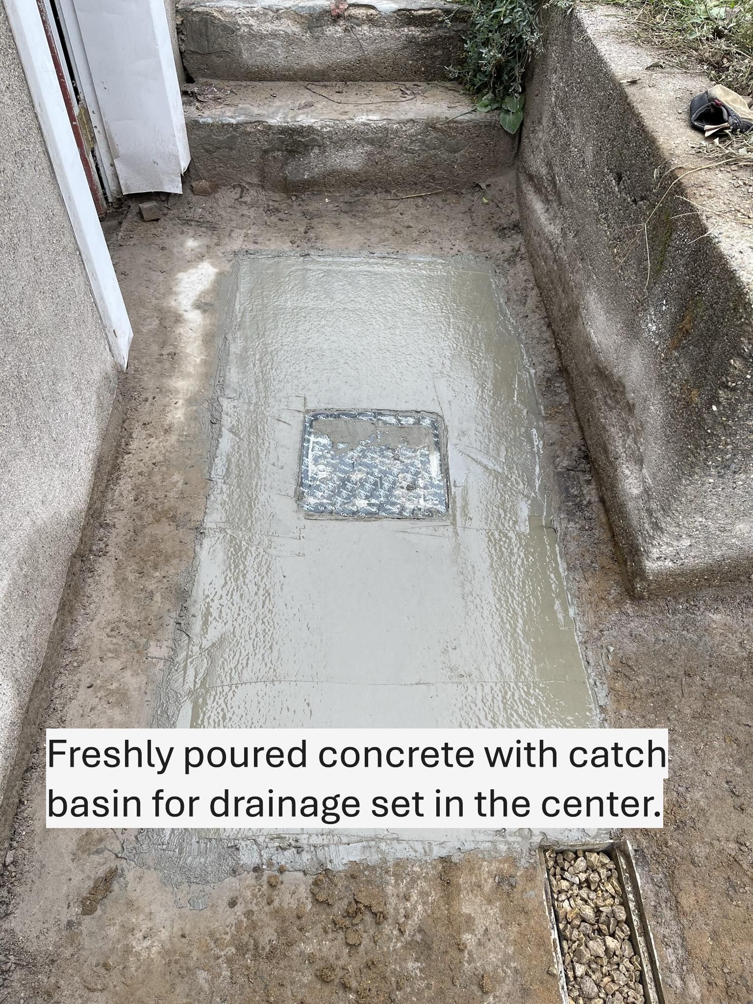Freshly poured concrete with a drainage catch basin in the center, set in an exterior recessed area.