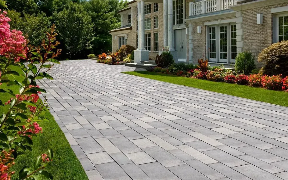 A large brick driveway leading to a large brick house.