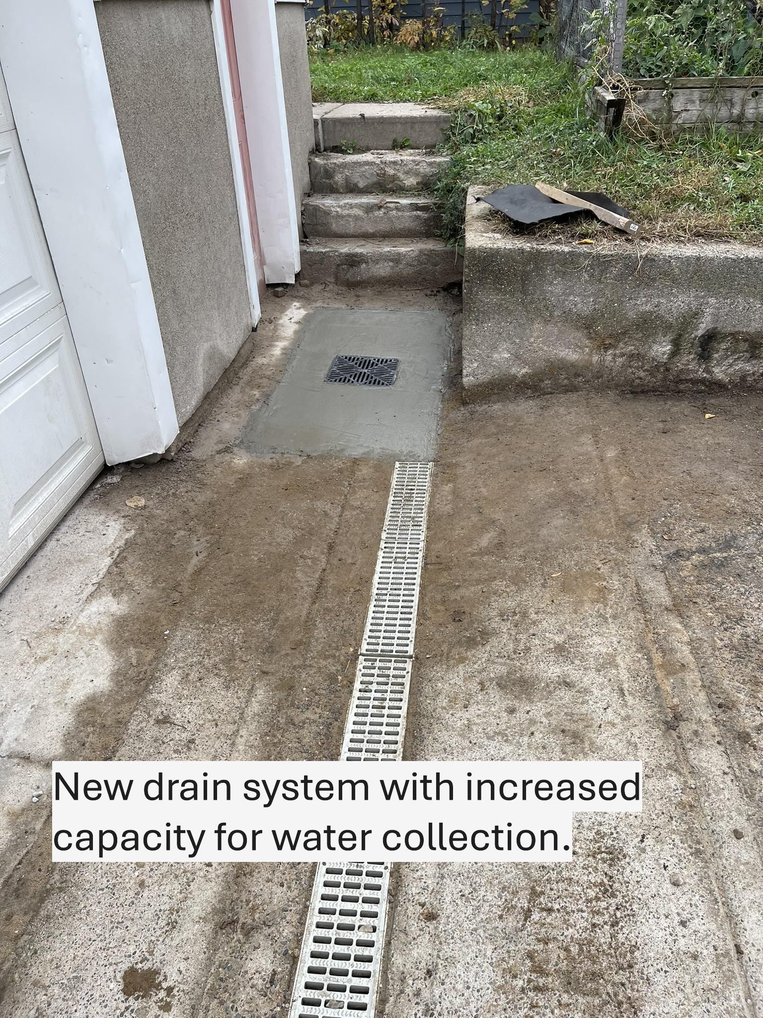 New concrete drain system for water collection, set into a driveway.