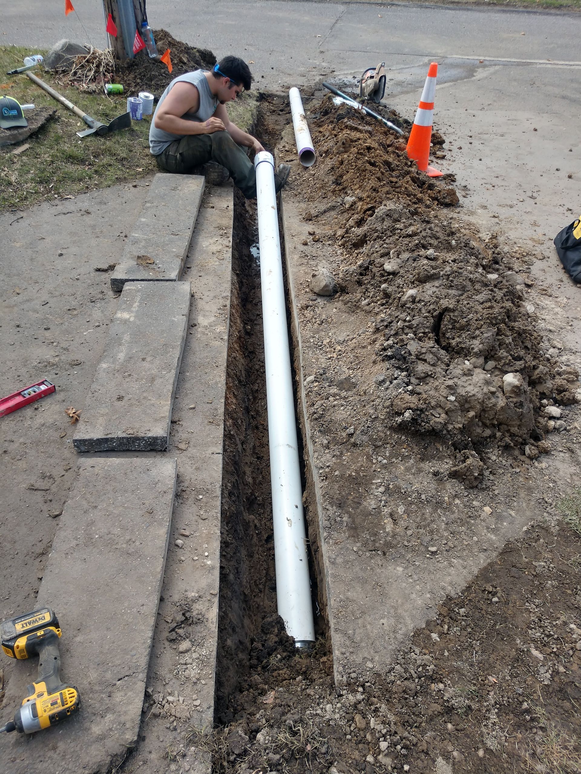 Our crew installing the underground drain pipe section that will discharge water from the French drains and downspouts into street