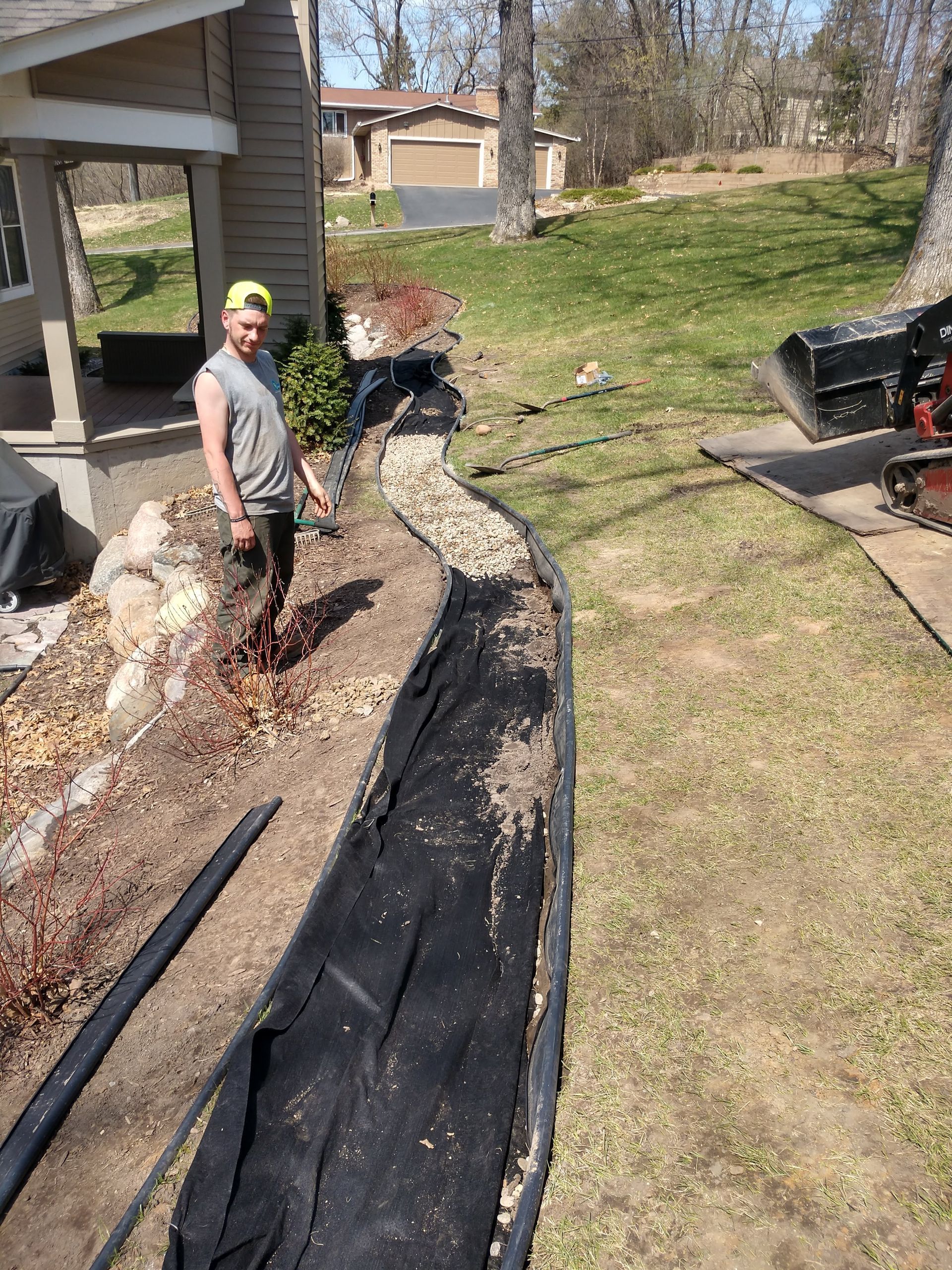 Our crew wrapping the French drain with fabric and starting to cover with rive rock
