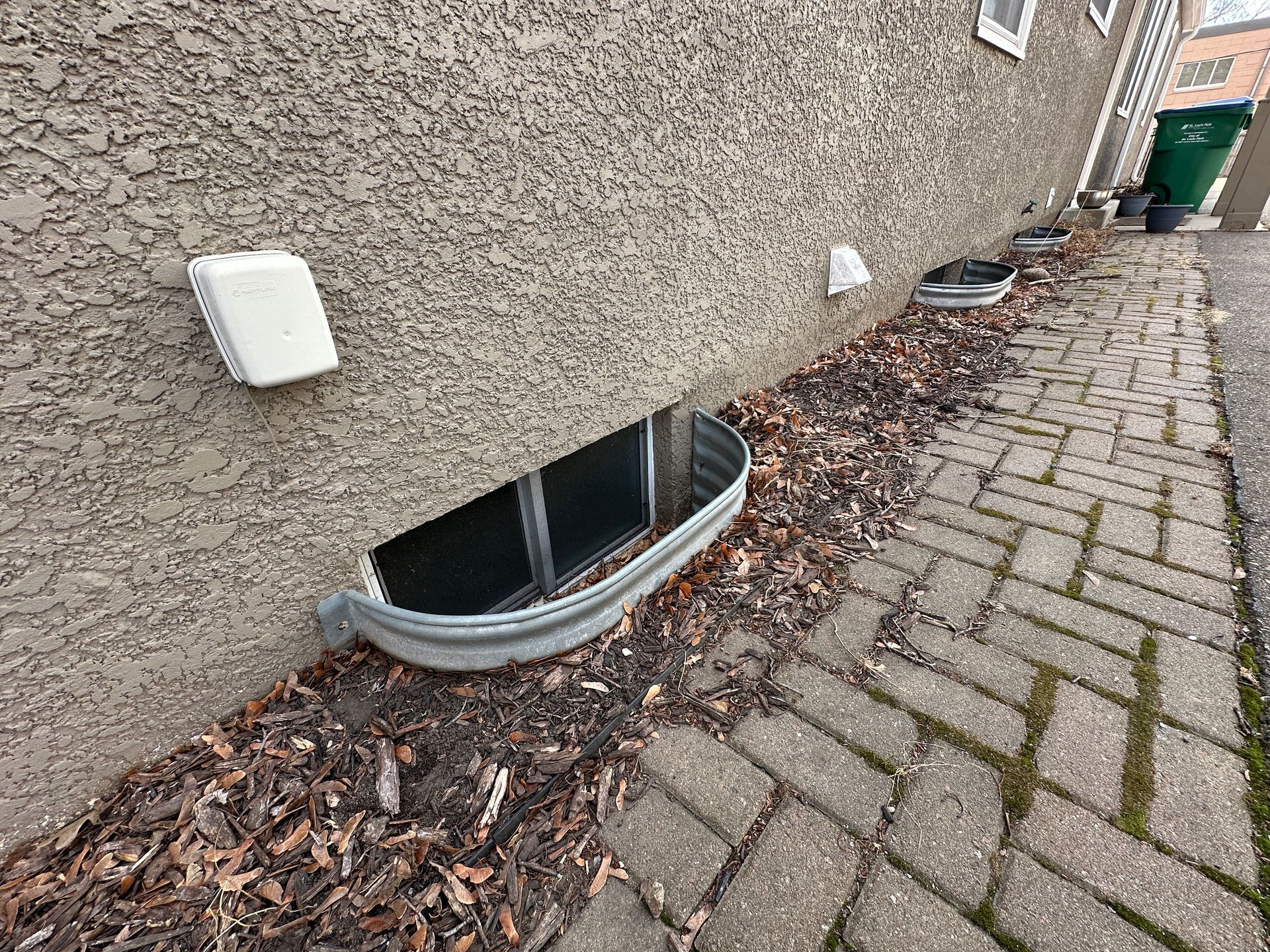 A picture of shallow window wells along the side of a house.