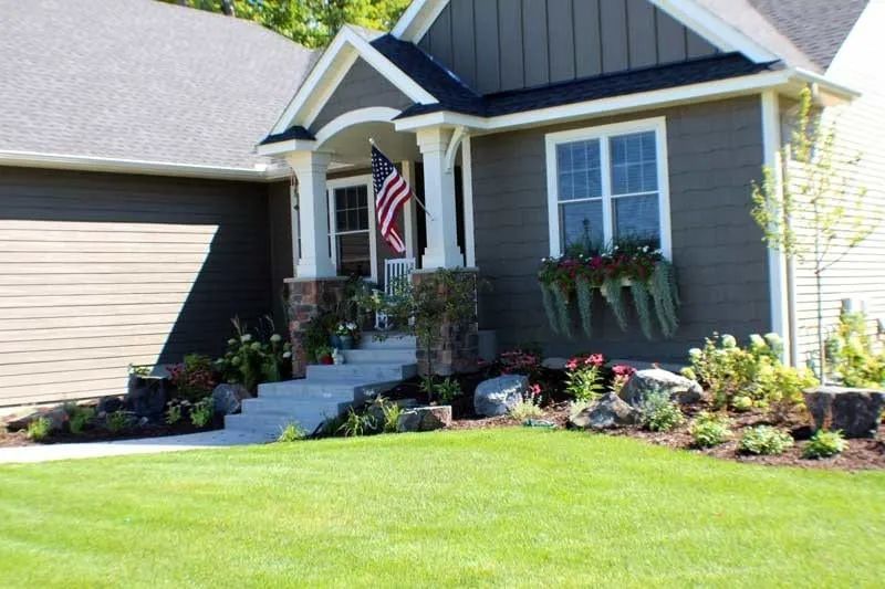 Front yard boulder outcropping landscaping with flowers colorful in Chanhassen MN colorful with interest all season long redbud tree American flag KG Landscape.com  