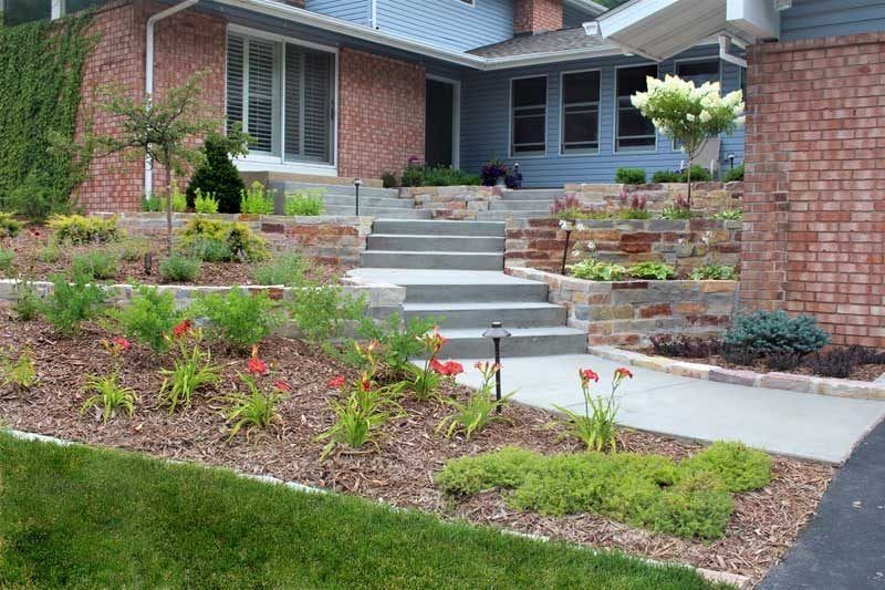 Front yard landscaping with natural stone walls concrete steps terraced flower beds flowering perennials  St. Paul MN KG Landscape on a hill sloped front yard 