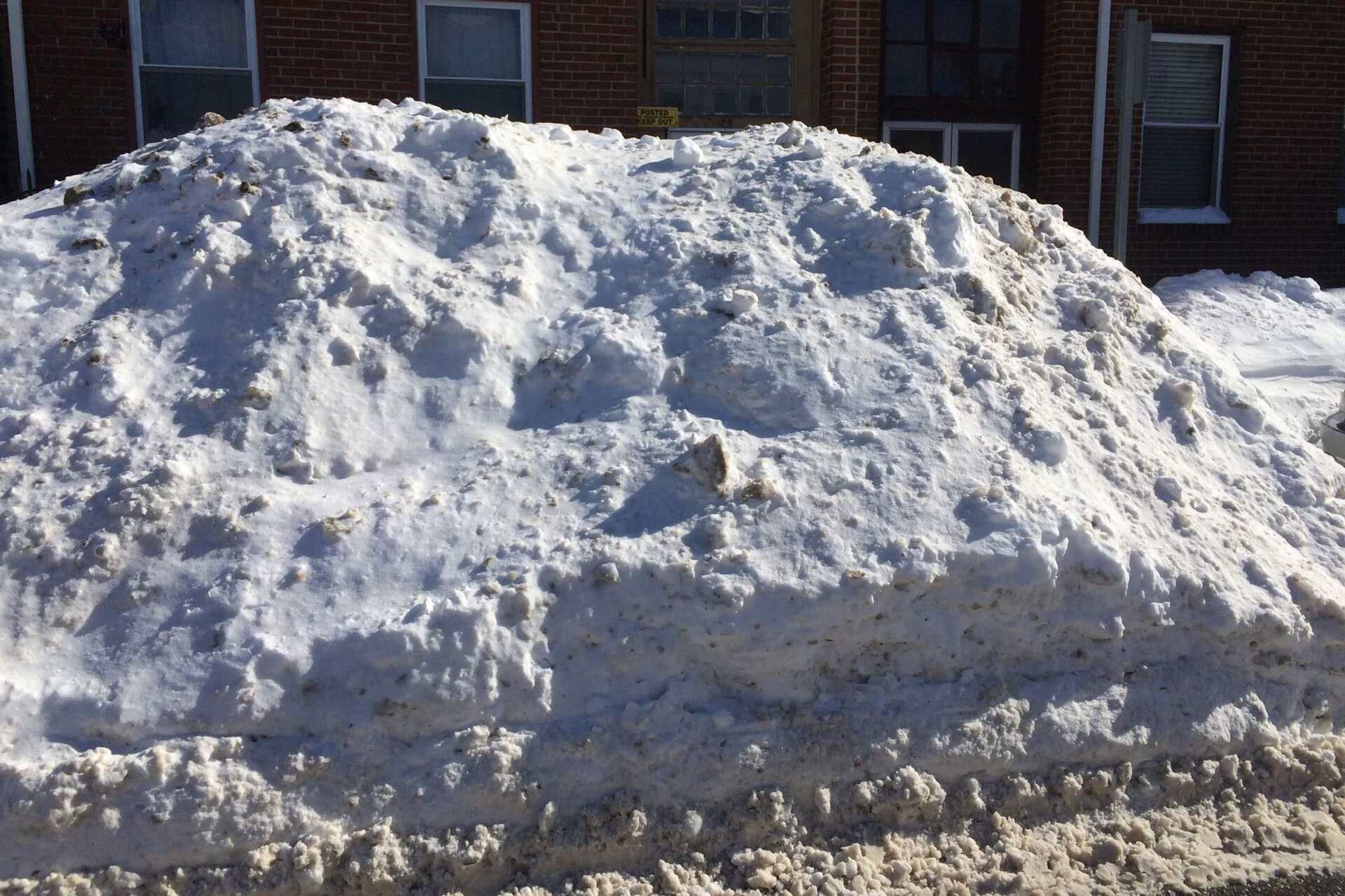 A large pile of snow in front of a brick building