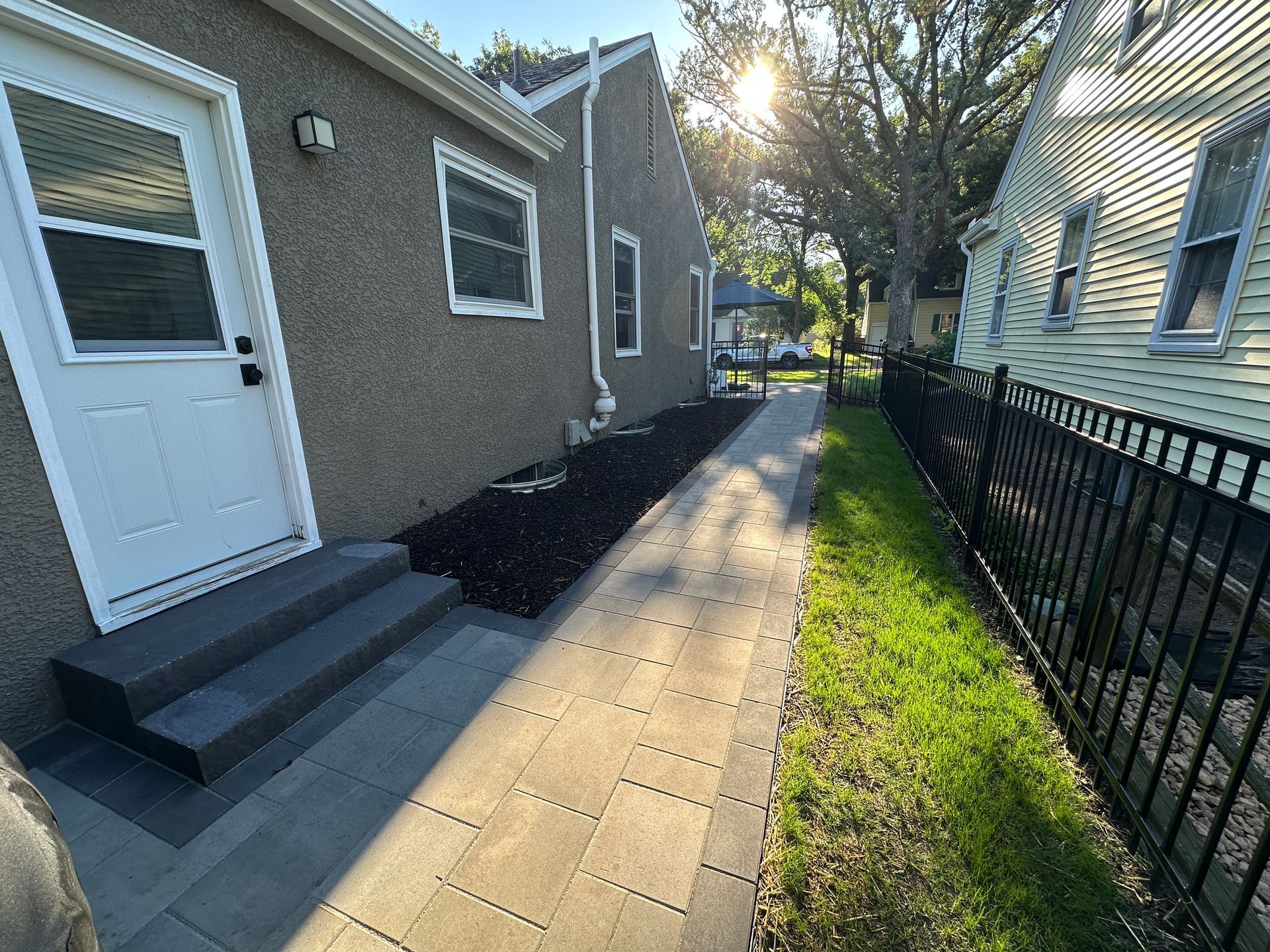 A new landing, repaved walkway, and improved drainage system create a gateway to the new patio.