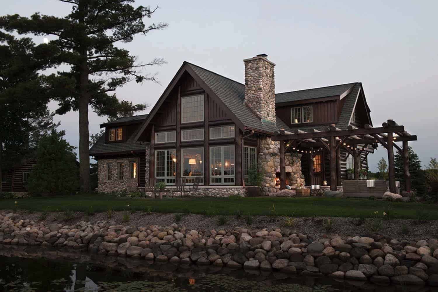 A large house with a lot of windows sits next to a body of water