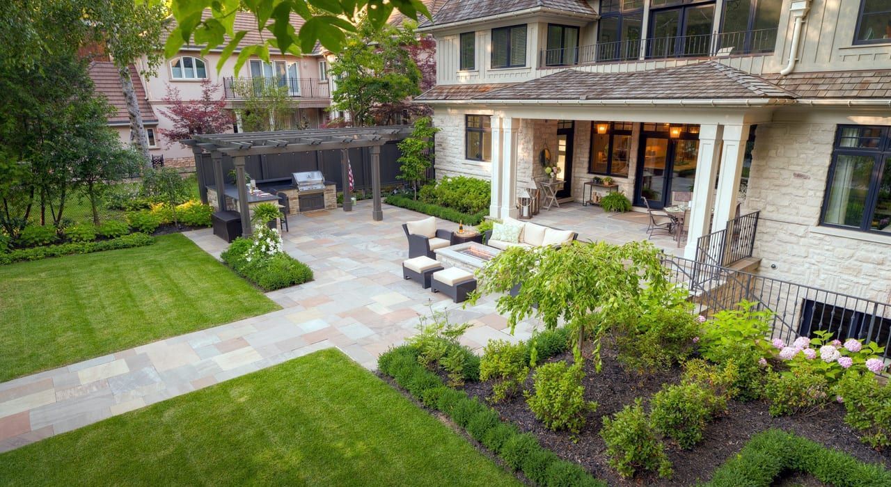 An aerial view of a large house with a lush green lawn and patio.