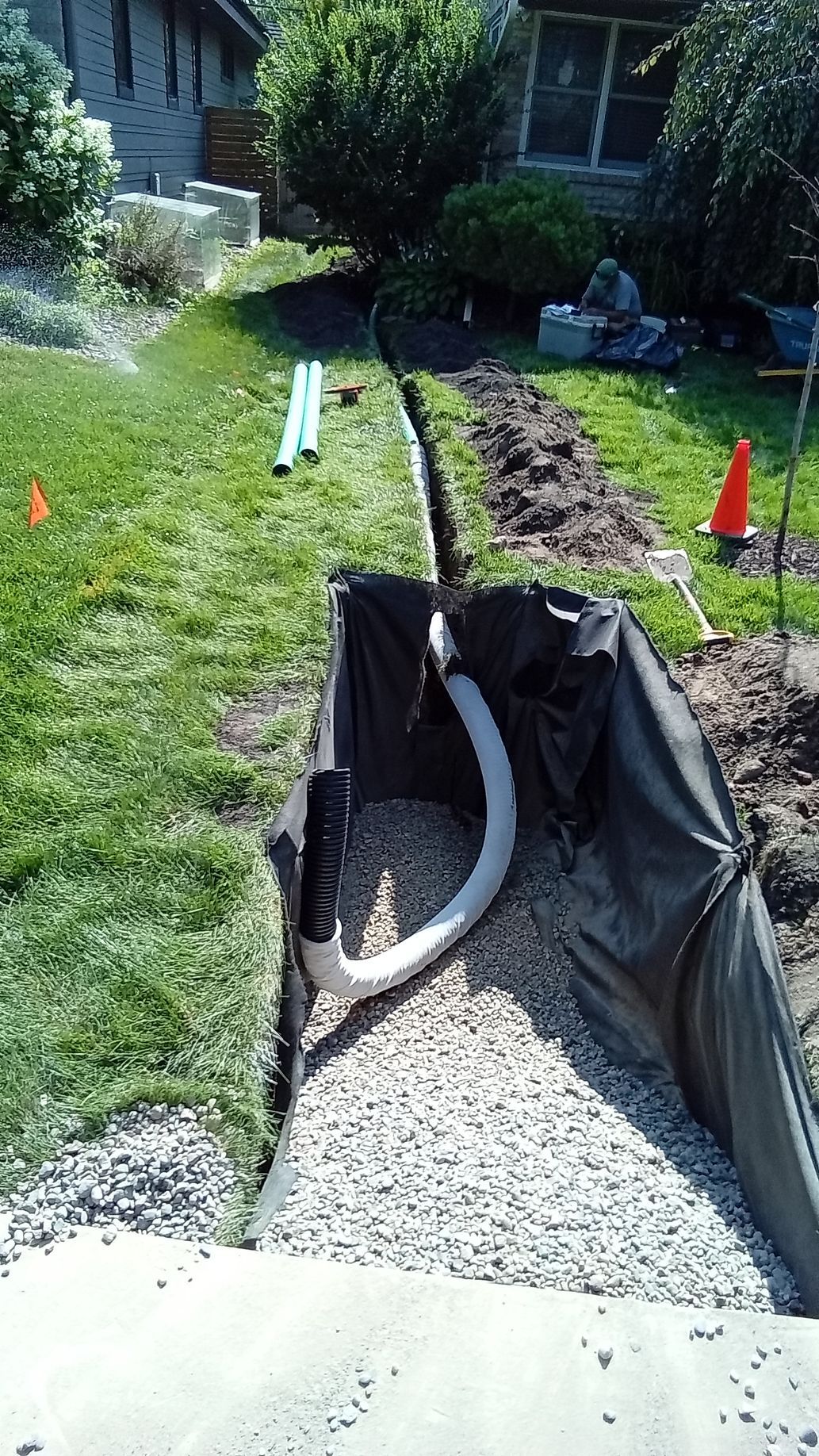 During: dry well pit basin being excavated lined with fabric and starting to fill bottom with rock