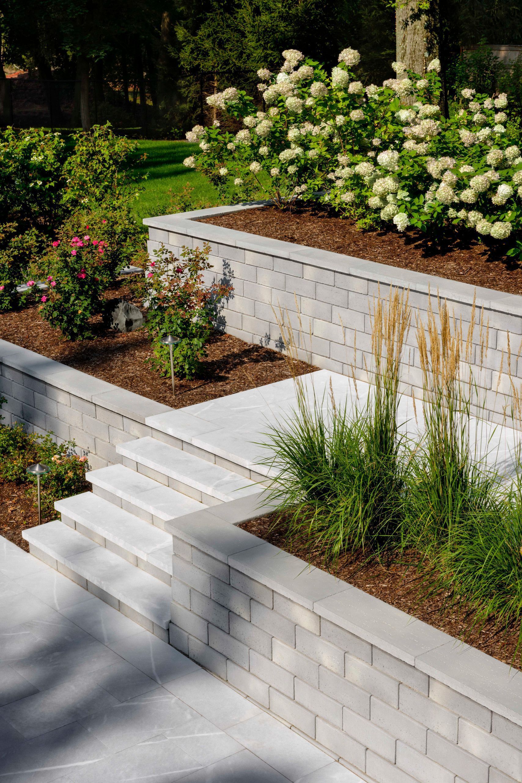 A brick wall is surrounded by plants and flowers in a garden.