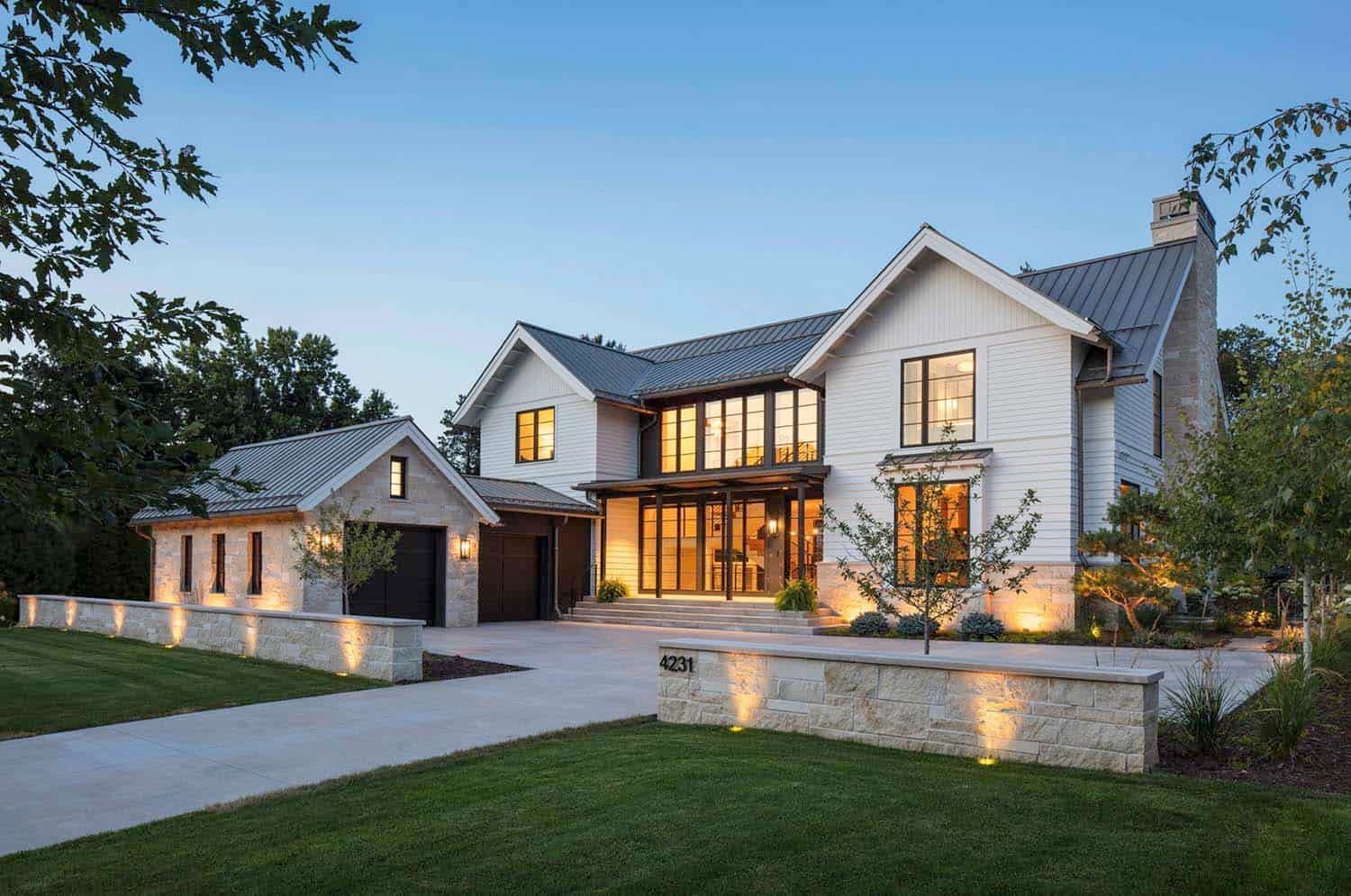 A large white house with a gray roof is sitting on top of a lush green lawn.