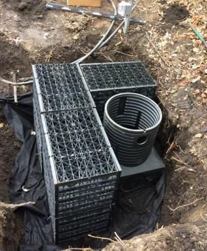 A drainage system is being installed in a hole in the ground.