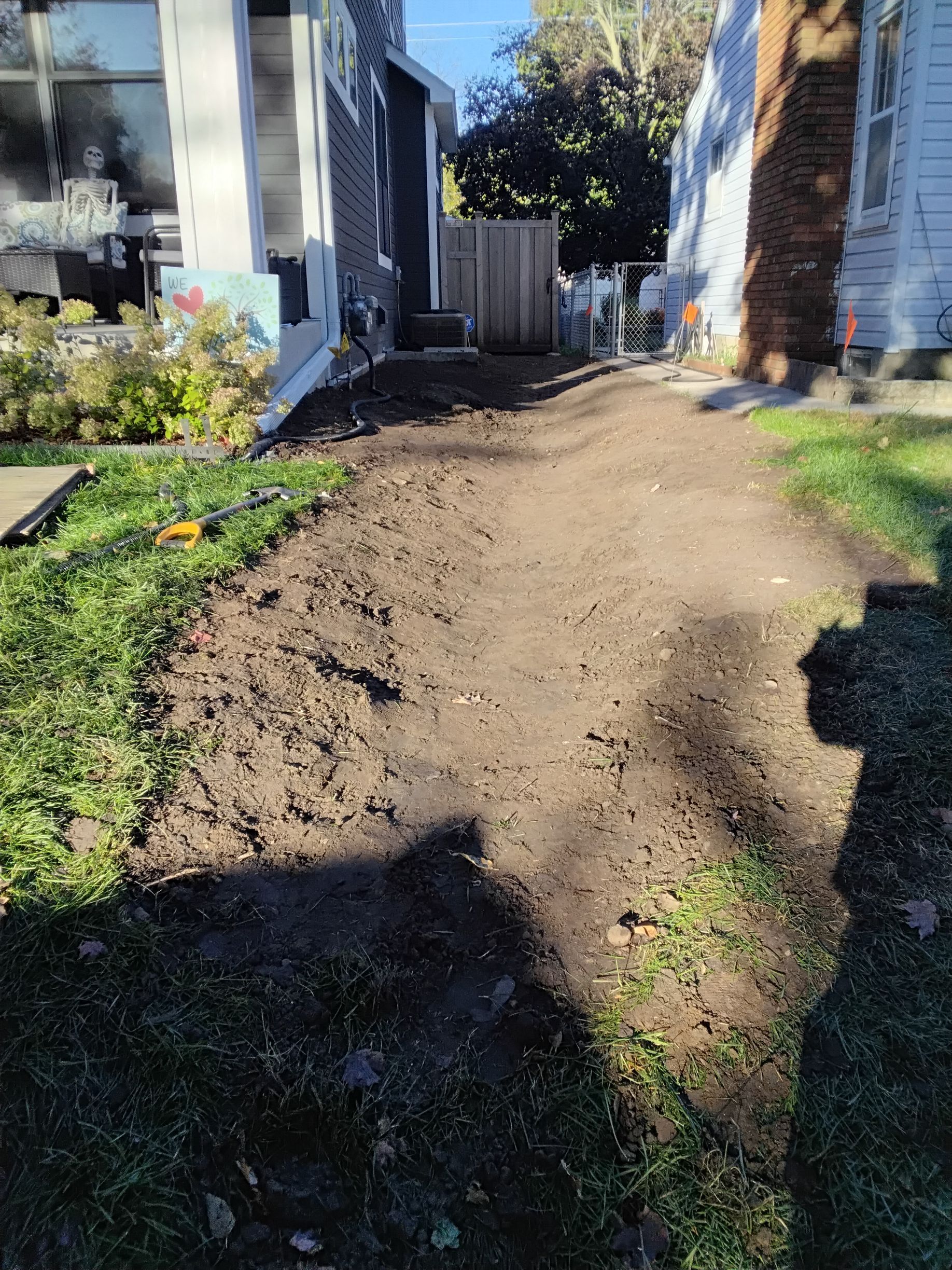 (During) after regrading the foundation bed-space to add slope in the soil away from the house - our crew graded a new side yard swale in the lawn between edging and property line to send water out of side yard to street in front 