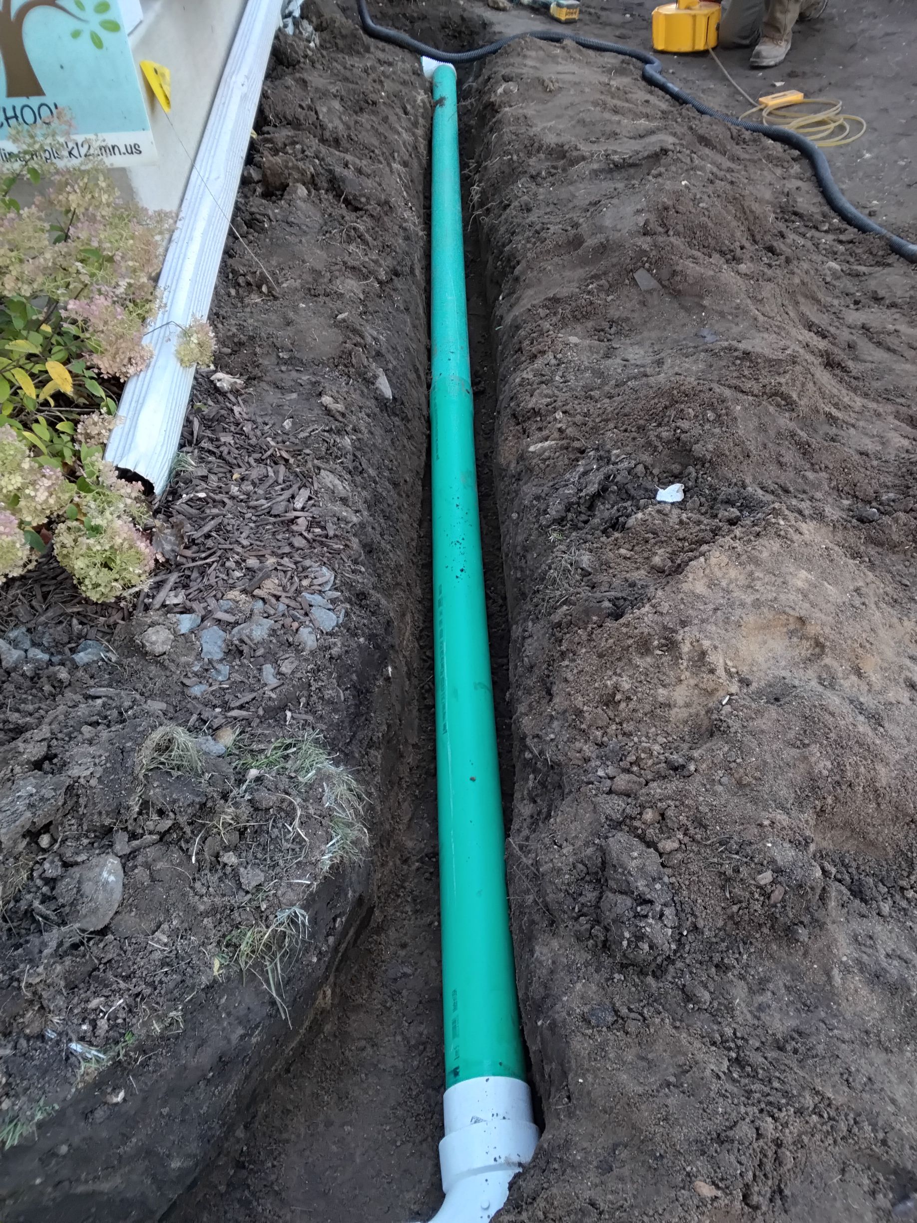 During picture of crew installing 4 inche PVC non perforated underground drain pipe with precise slope for a Minneapolis Drainage fix job