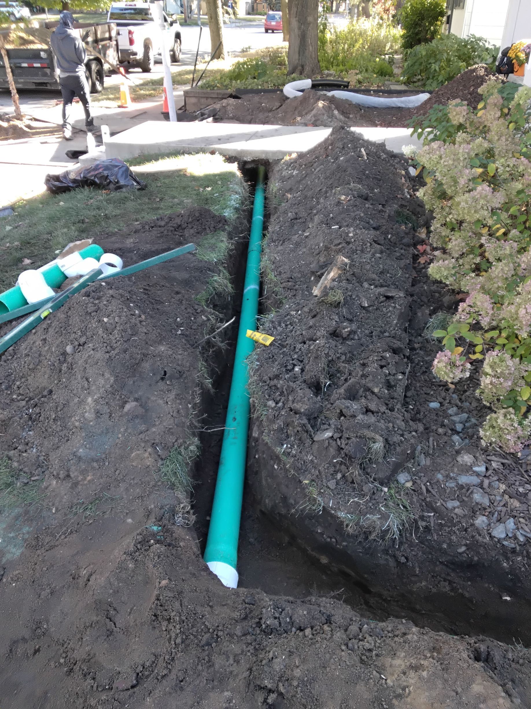 During picture of crew installing 4 inche PVC non perforated underground drain pipe with an elbow setting precise slope for a Minneapolis Drainage fix job