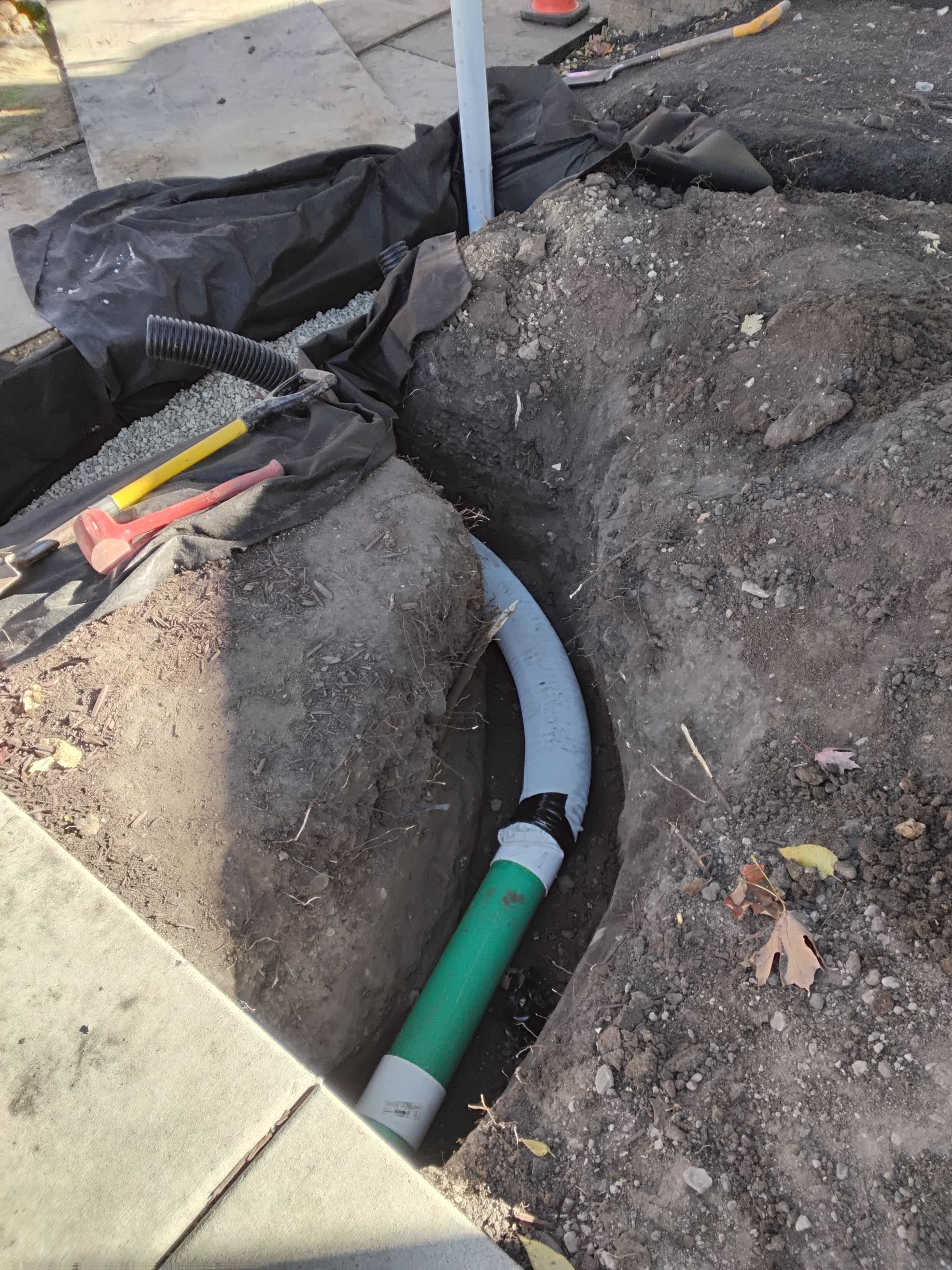 During: installing the sump pump water discharge pipe into the dry well