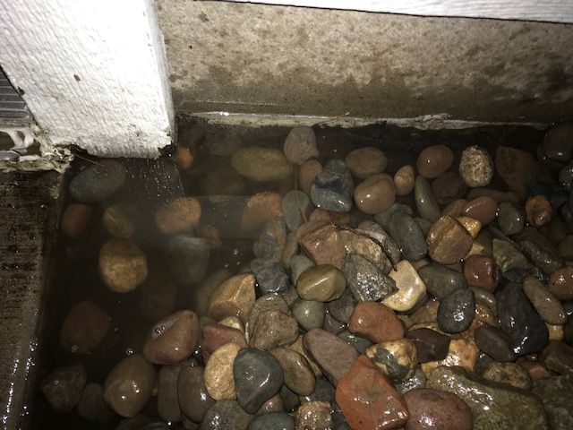 water pooling in a rock bed right up against the house water problem in landscaping