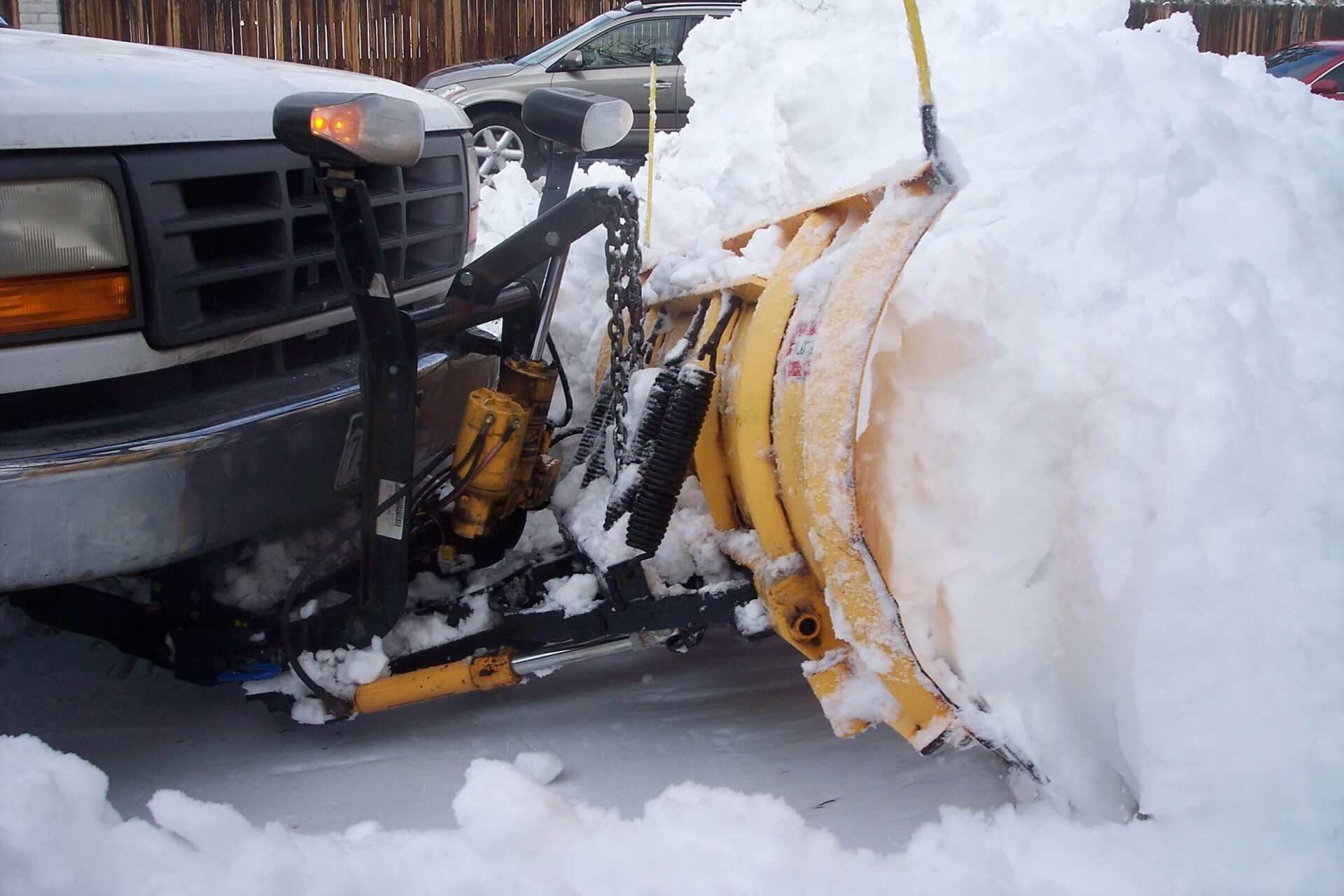 A snow plow is clearing snow from a parking lot.