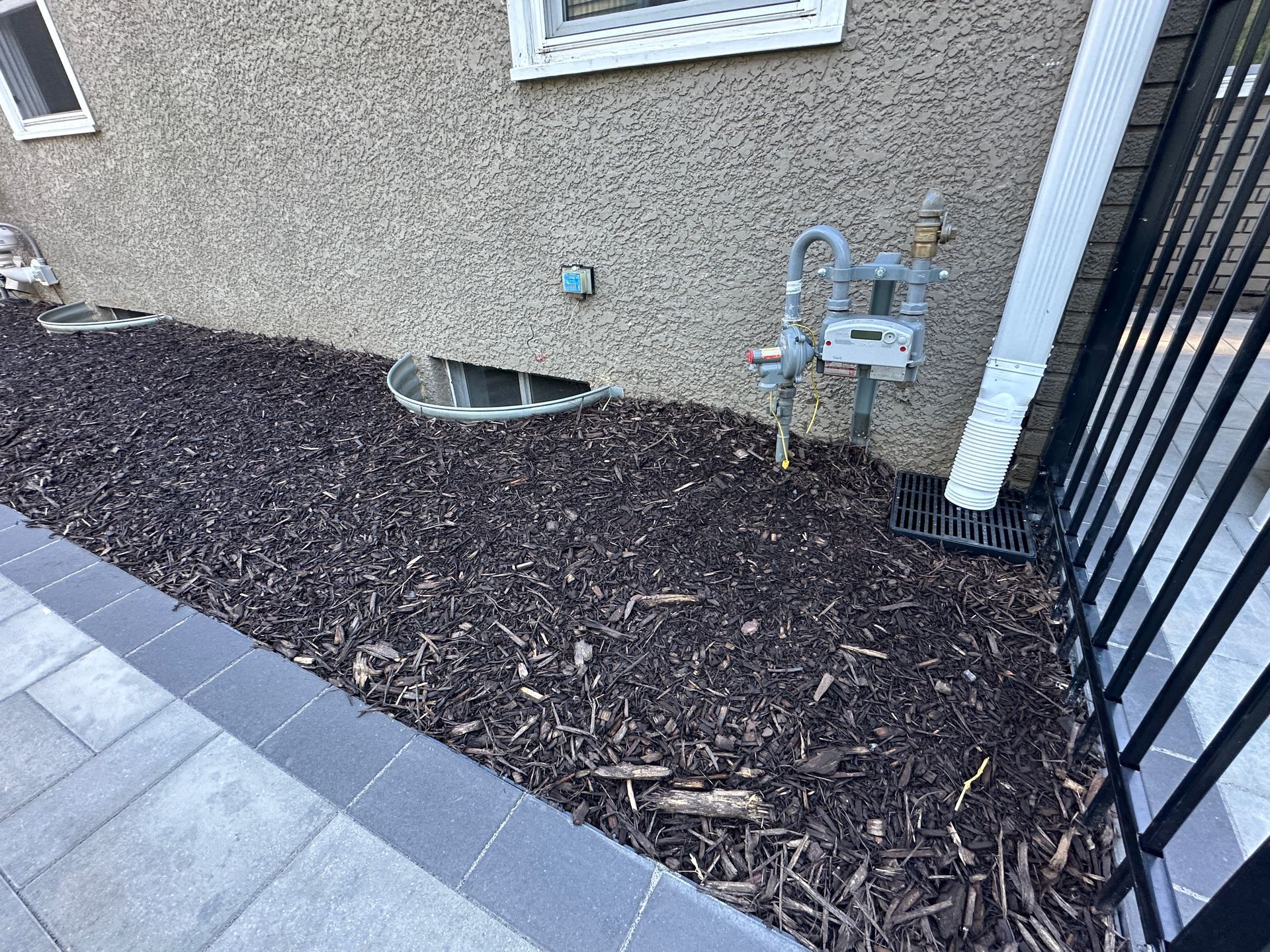 Underground downspout drain system in the landscaping at corner of garage running below front walkway in MN 