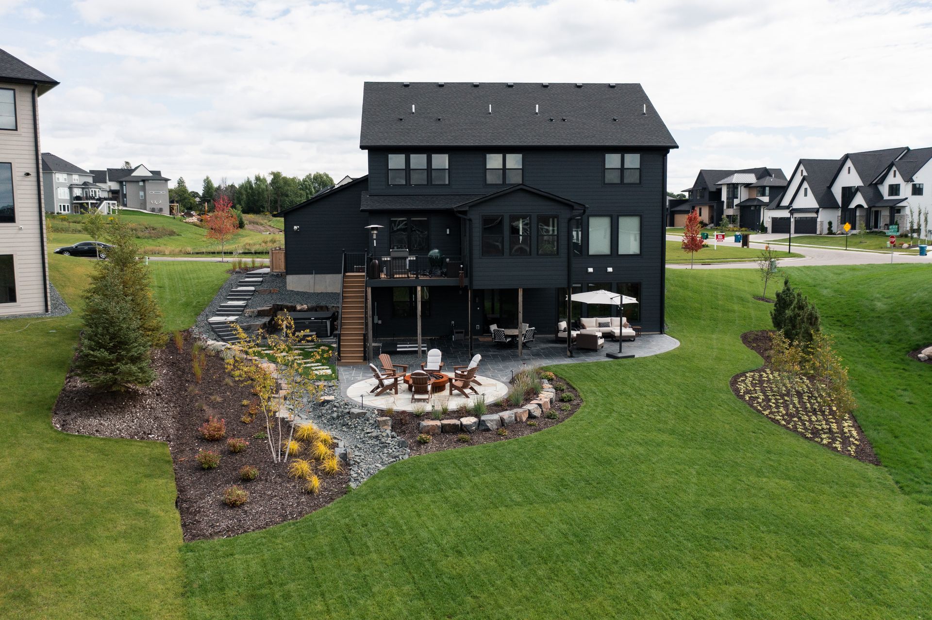 Full backyard view of new build design with custom back yard including fire pit and walkout patio. 