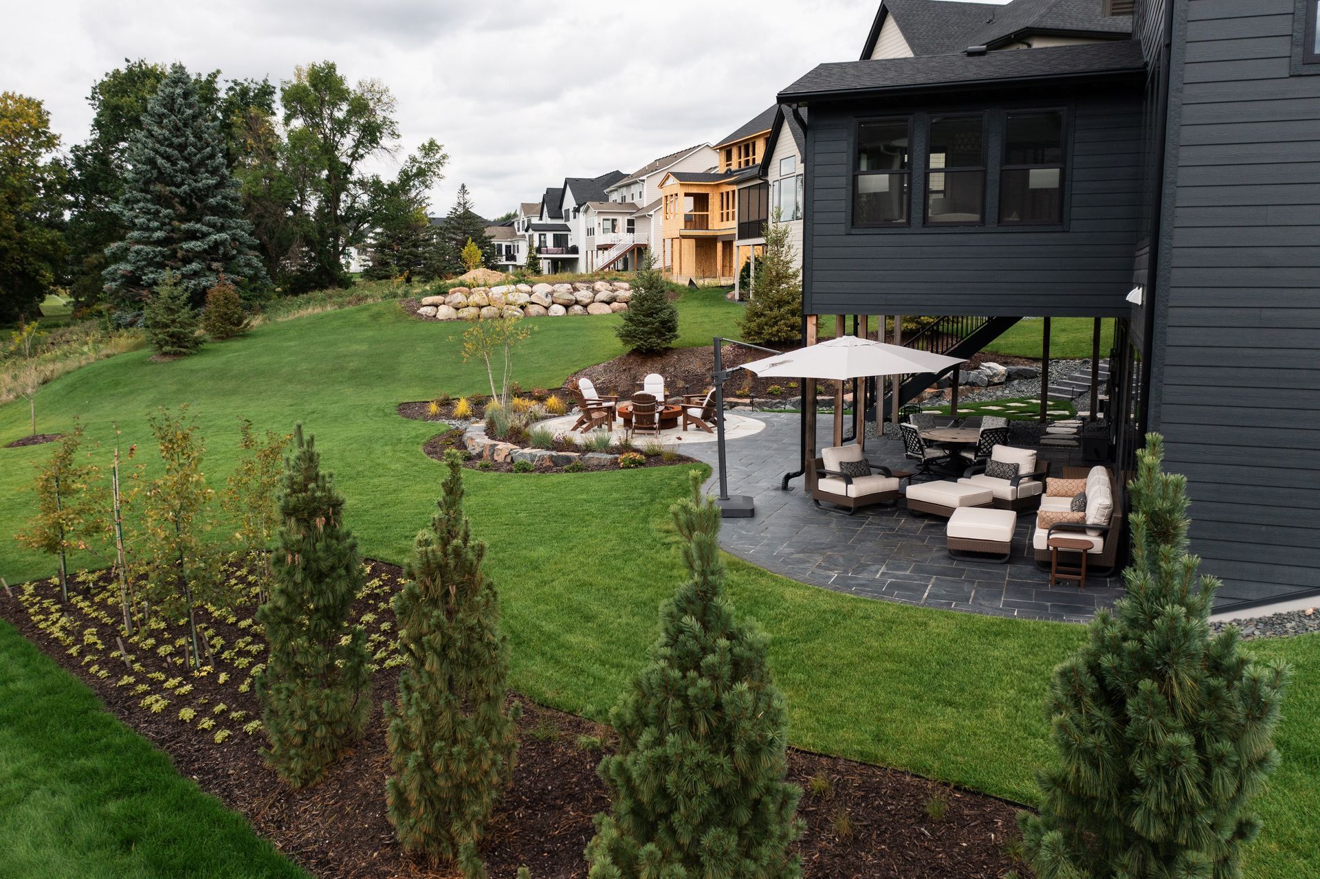 Side yard view of a walk out patio with custom fire pit design in Minnesota. 