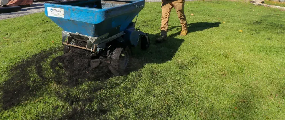 lawn spreader applying rich topdressing soil to a lawn in MN 