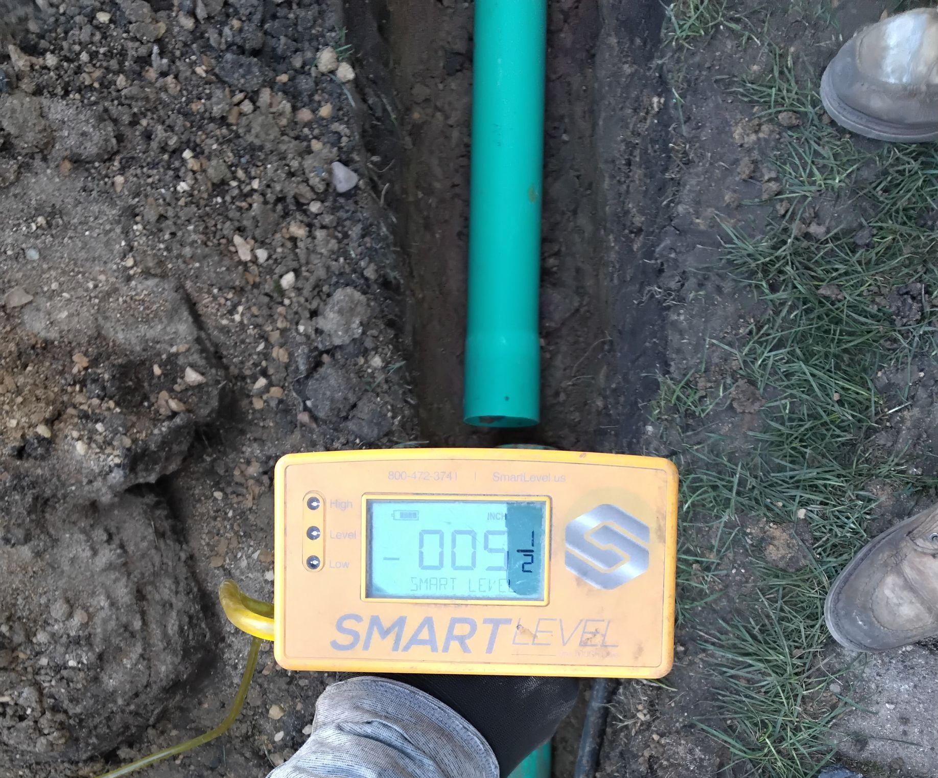 KG Landscape crew installing PVC drain pipe and using altimeter to measure the slope in the pipe 