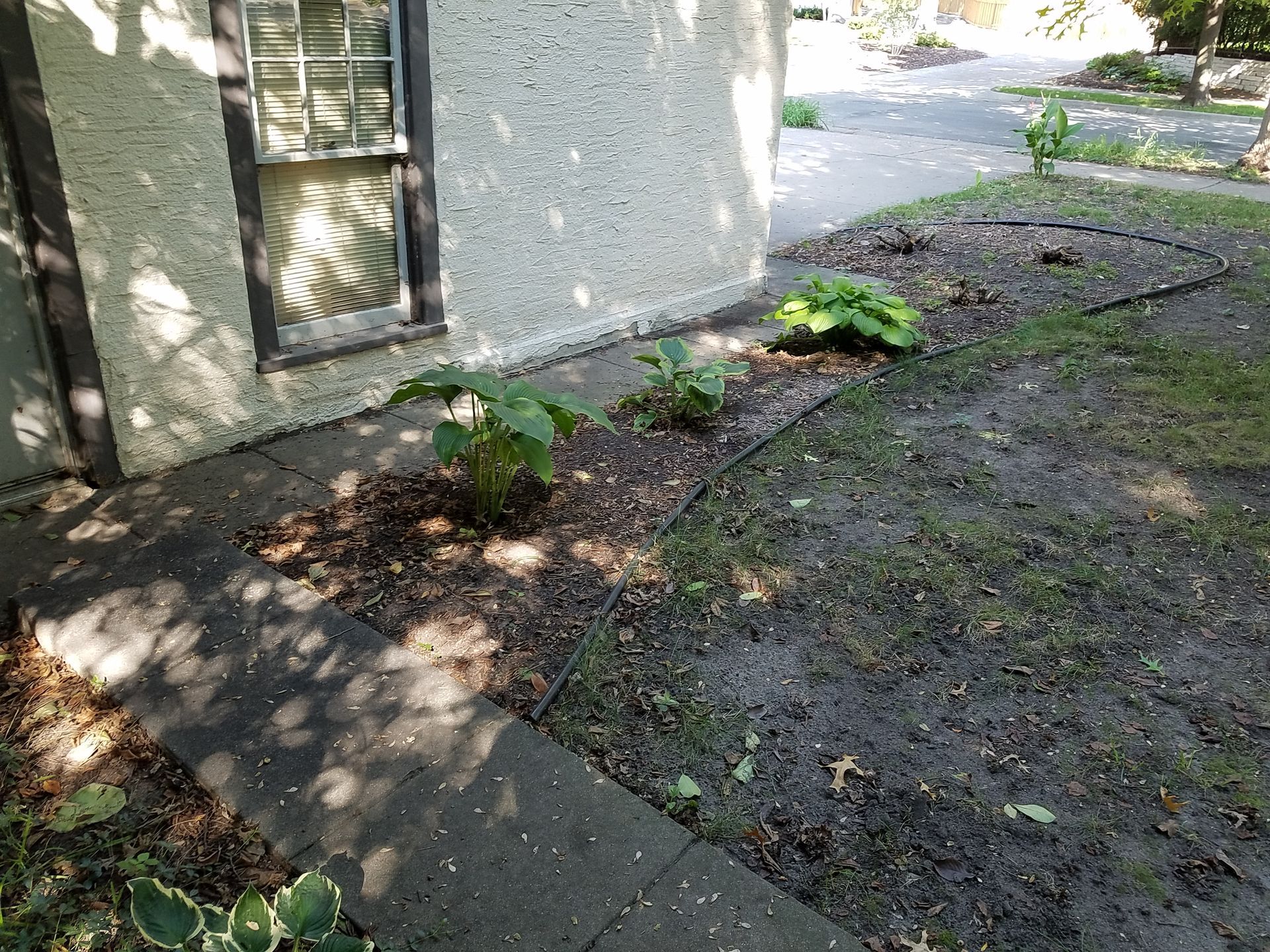 Before photo of water running downhill toward garage foundation showing need for drainage repair in Minneapolis