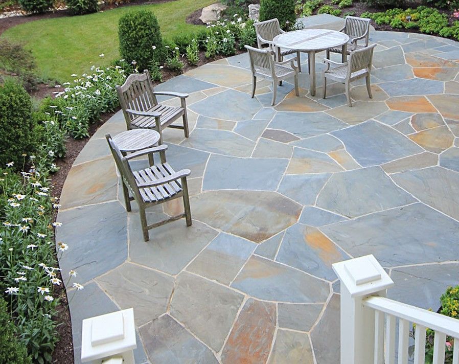 A stone patio with a table and chairs on it