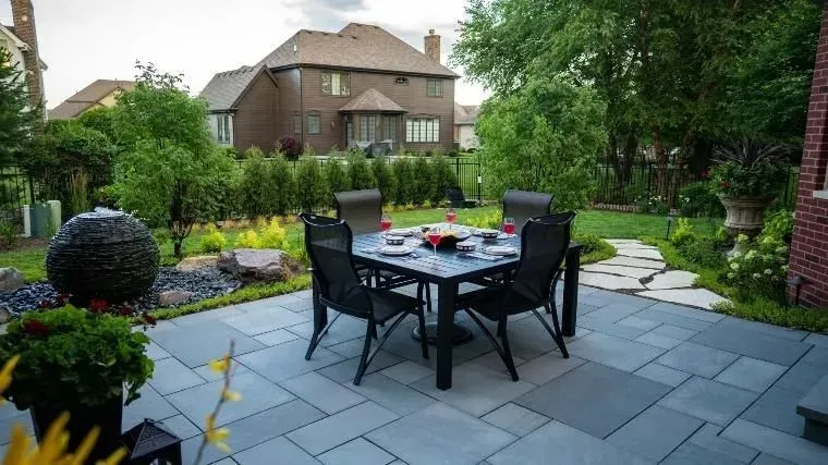 A patio with a table and chairs in front of a house.