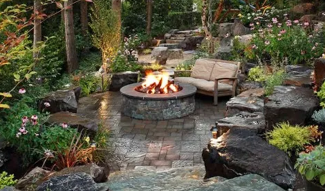 Boulder fire pit backyard with chairs on flagstone patio by the water in MN
