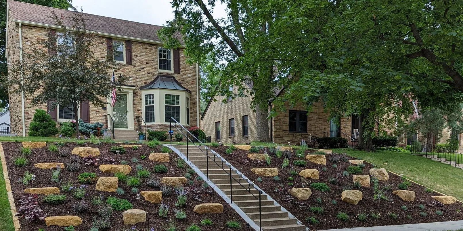 Front yard boulder outcropping landscaping with limestone on a hill sloped yard in Minneapolis Minnesota KG Landscape.com