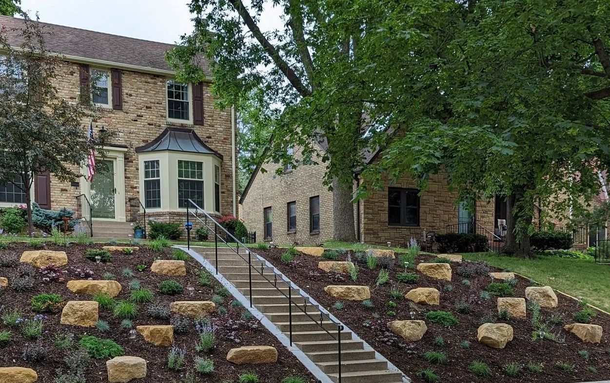 A large house with a lush green lawn and flowers in front of it.