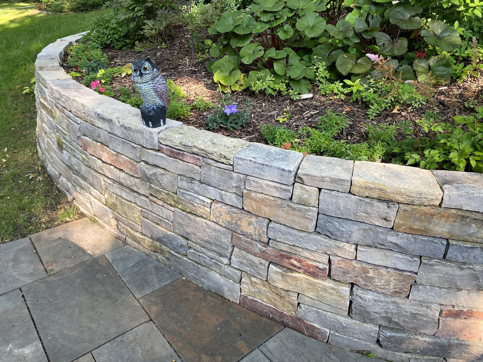 A stone wall with flowers growing on it in a garden.
