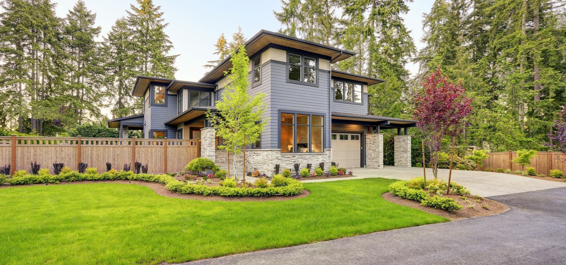 A large house with a lush green lawn and trees in the background.