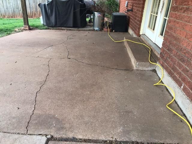 A cracked concrete patio with a yellow power cord attached to it.