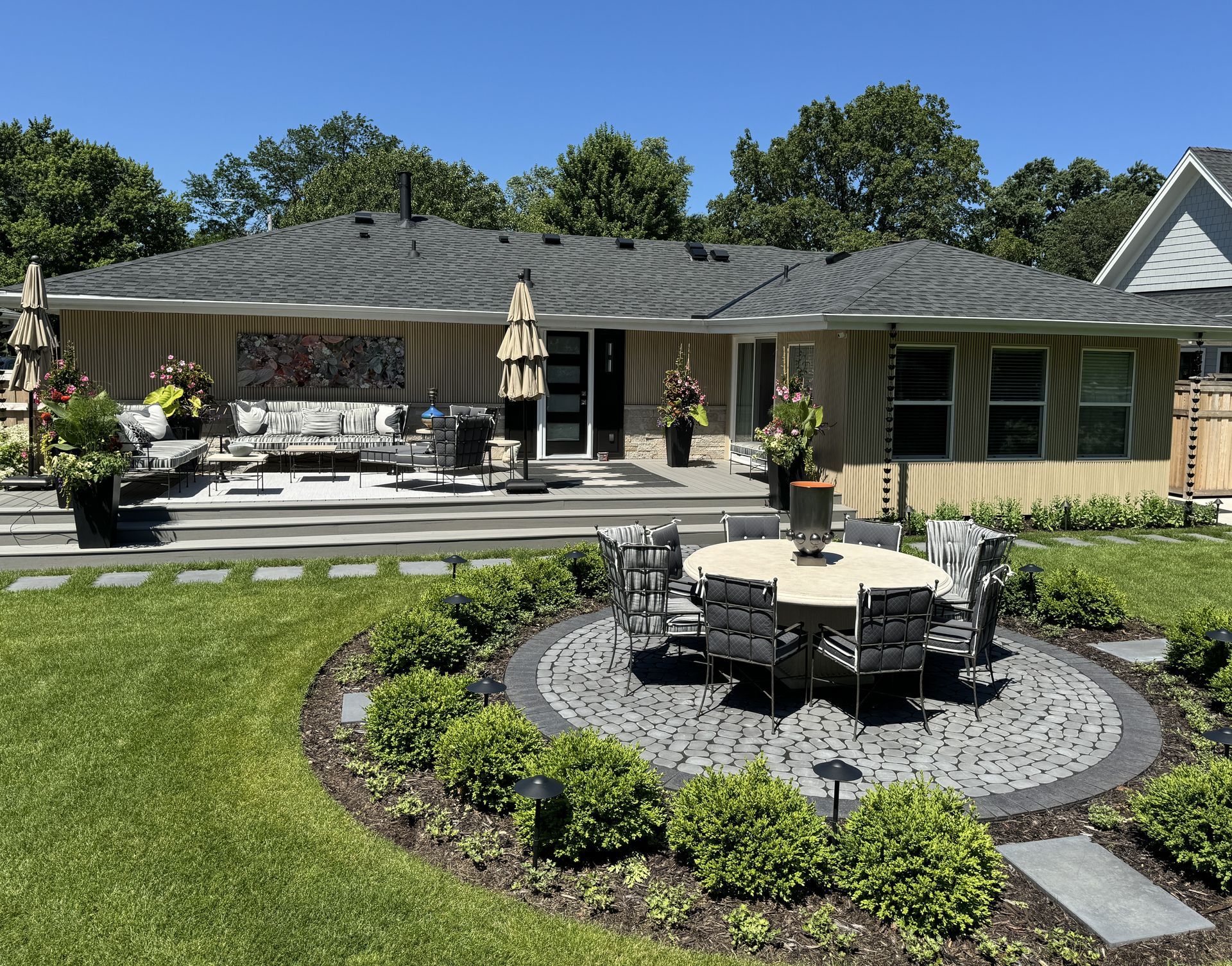 Dream backyard outdoor living space with maintenance free deck of patio door with landing and steps down to patio with dining set at lawn grade project by KG Landscape in Edina MN 