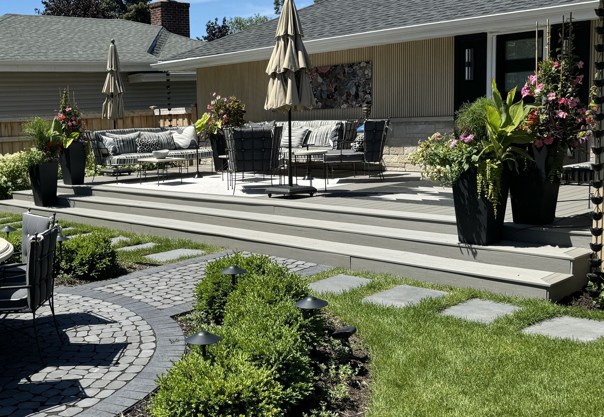 Dream backyard outdoor living space with maintenance free deck of patio door with landing and steps down to patio with dining set at lawn grade project by KG Landscape in Edina MN 