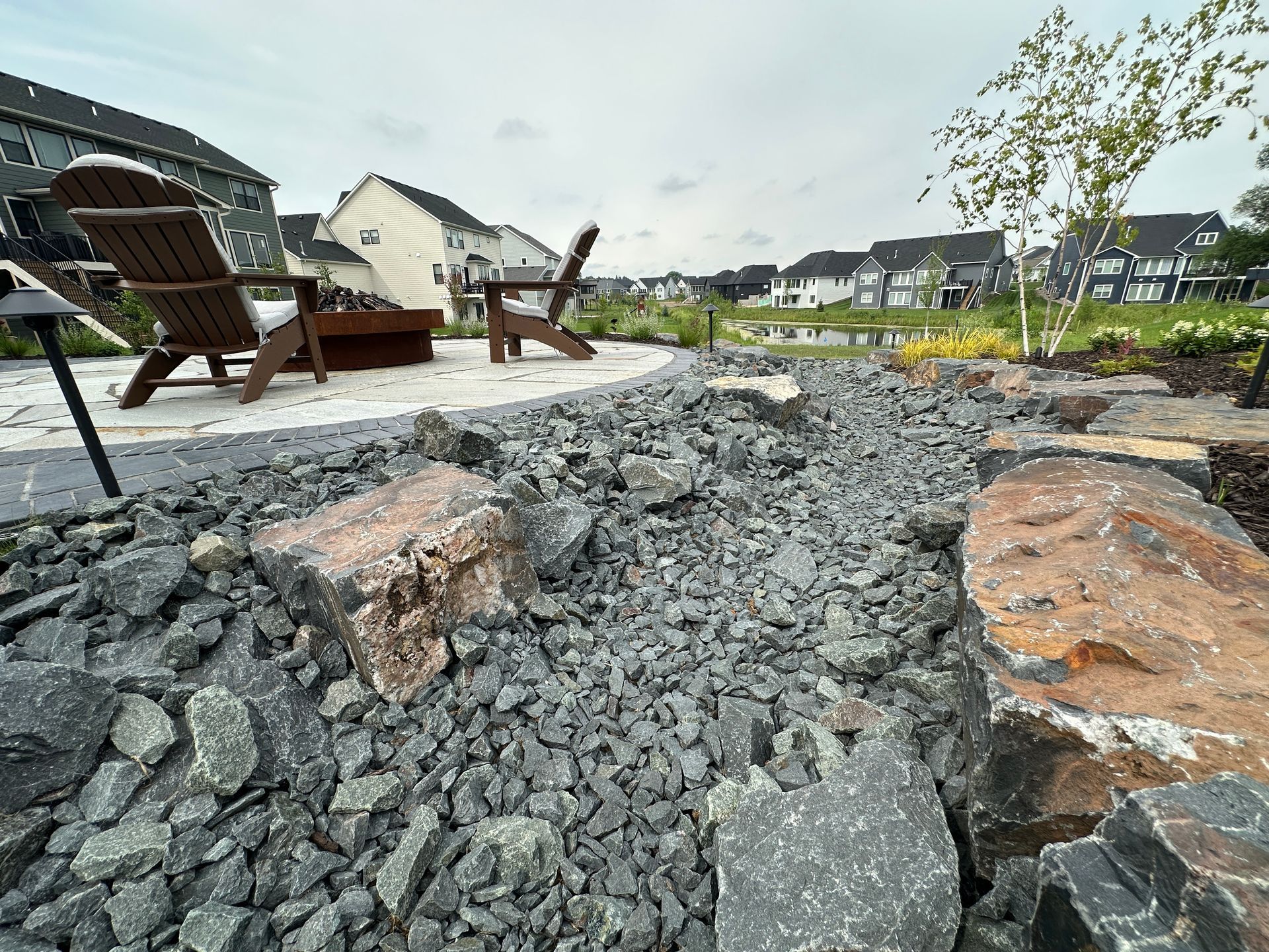 Very nice landscaping with dry creek bed using trap rock around raised patio in Maple Grove KG Landscape