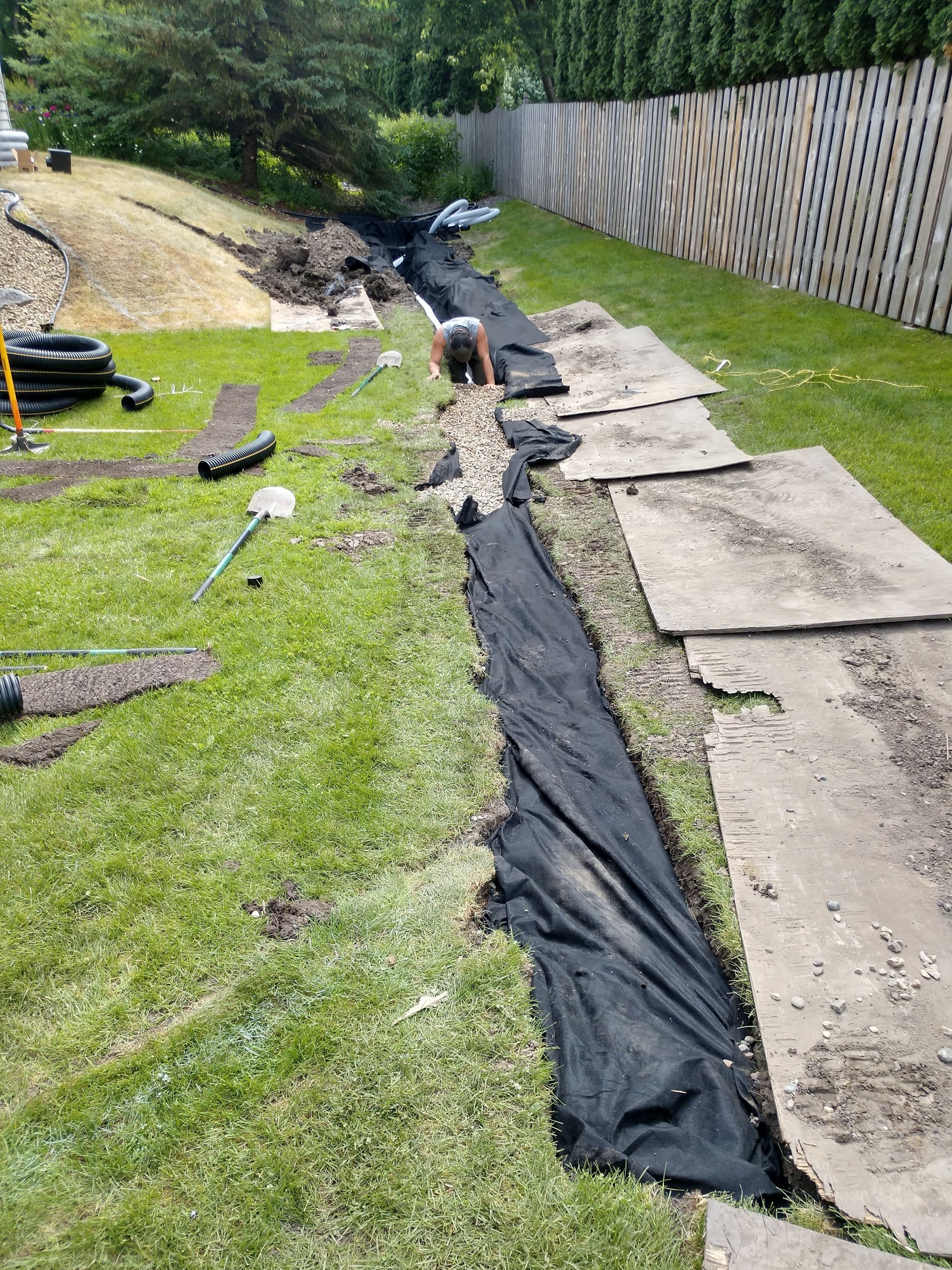 New landscape drainage system being installed primary French drain in the swale  