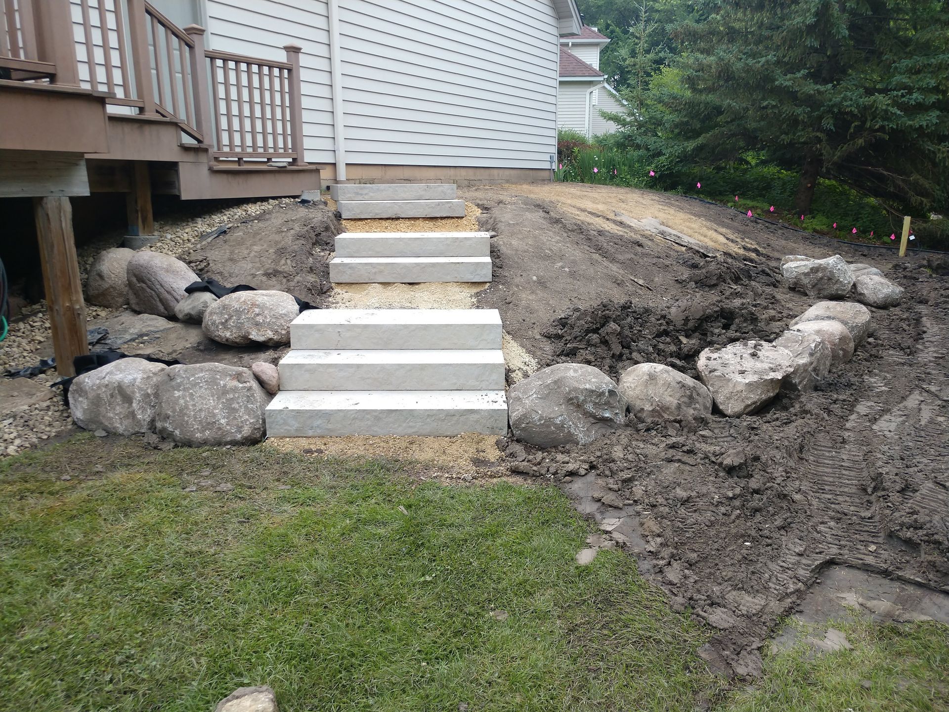 New Hillside steps with boulder wall and sloped area plantings being installed 