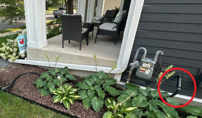 Black hose near home's exterior wall wrong way to discharge sump pump water outside