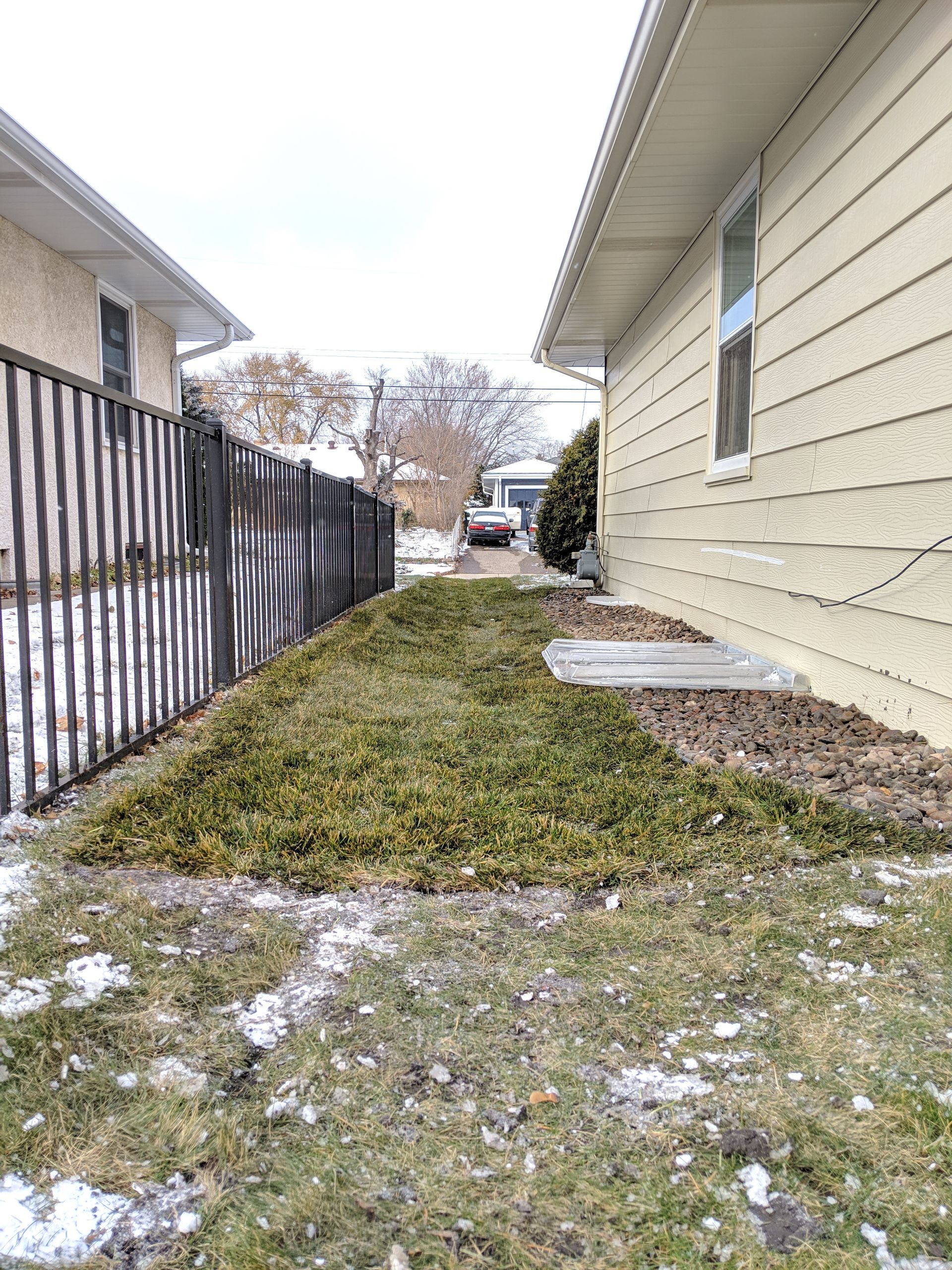New side yard grading swale repaired with sod and regraded foundation landscaping for improved drainage