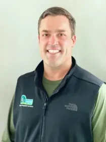 A man wearing a north face vest is smiling for the camera.