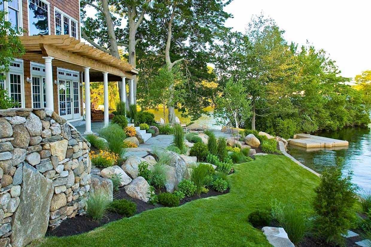 A house with a large lawn in front of it next to a body of water.