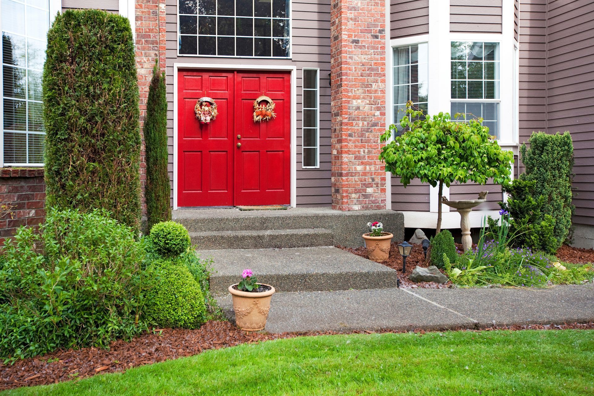 A house with red doors and a lush green lawn