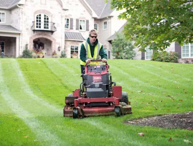 crew member mowing a green lawn