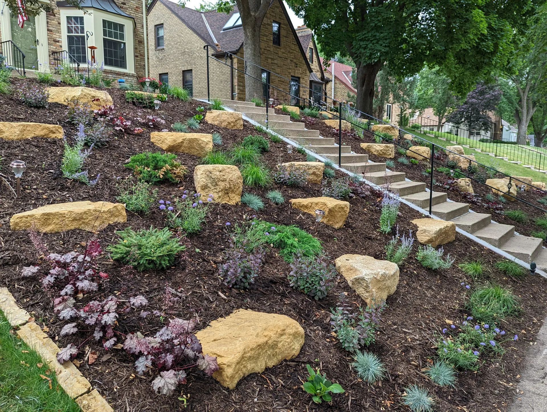 Front yard boulder outcropping landscaping on a hill sloped yard in Minneapolis Minnesota KG Landscape.com limestone and brown mulch