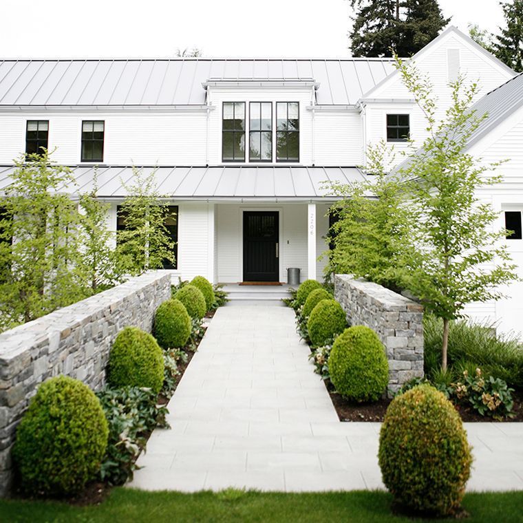 A white house with a black door and a stone wall